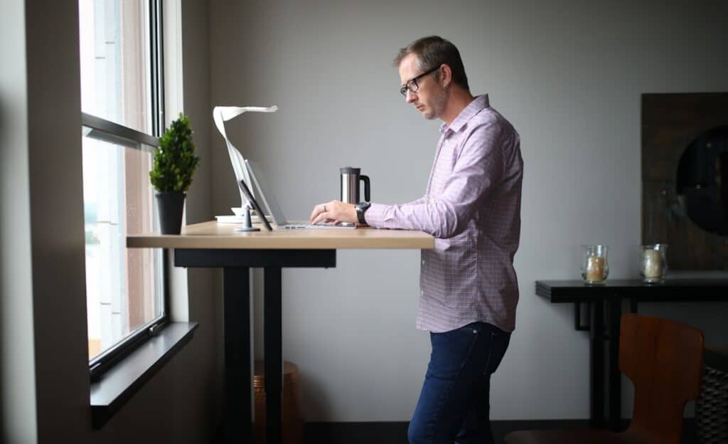 Man at a standing desk managing a steady day as part of daily autoimmune disease support